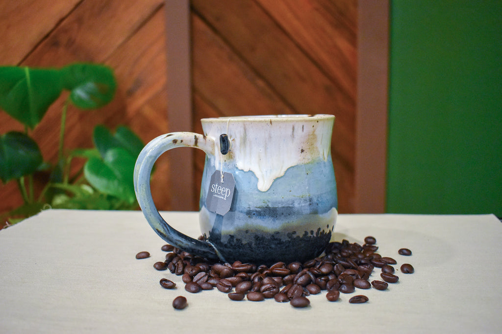 Hand-thrown mug in Snowmelt, cream drips over sky blue deepening to a charcoal base