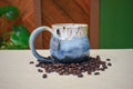 Hand-thrown mug in Snowmelt, cream drips over sky blue deepening to a charcoal base