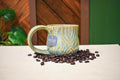 Hand-thrown mug carved with bark-like grain lines in Ivy, sage and soft blue-grey glaze with honey-gold highlights