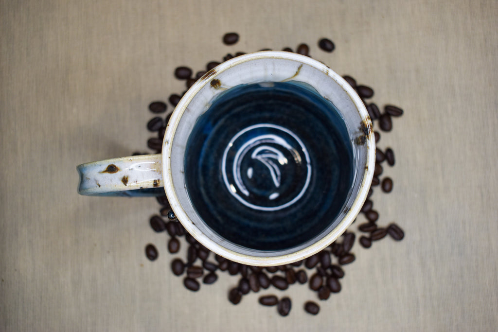 Hand-thrown mug in Snowmelt, cream drips over sky blue deepening to a charcoal base