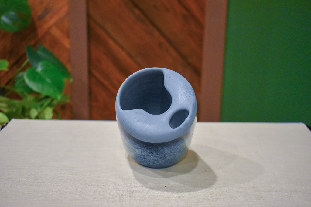 Hand-thrown ceramic travel mug in Blue Drift, matte pale slate blue lid over deep ink blue breaking to pale blue froth over cobalt