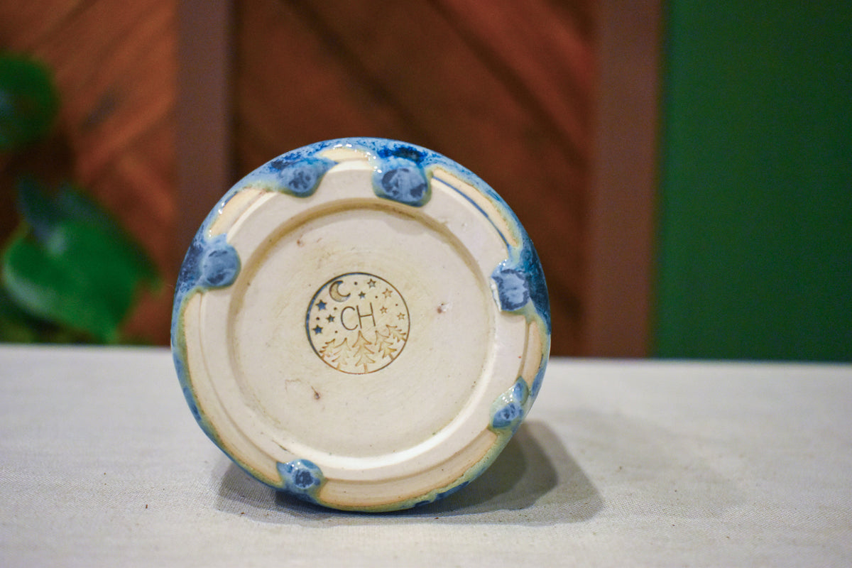 Hand-thrown ceramic travel mug in Blue Drift, matte pale slate blue lid over deep ink blue breaking to pale blue froth over cobalt