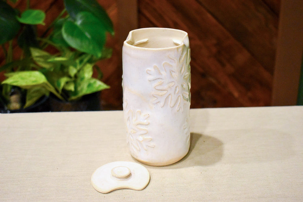 Hand-thrown vase in soft cream-white glaze with raised hand-carved snowflakes and a ceramic lid