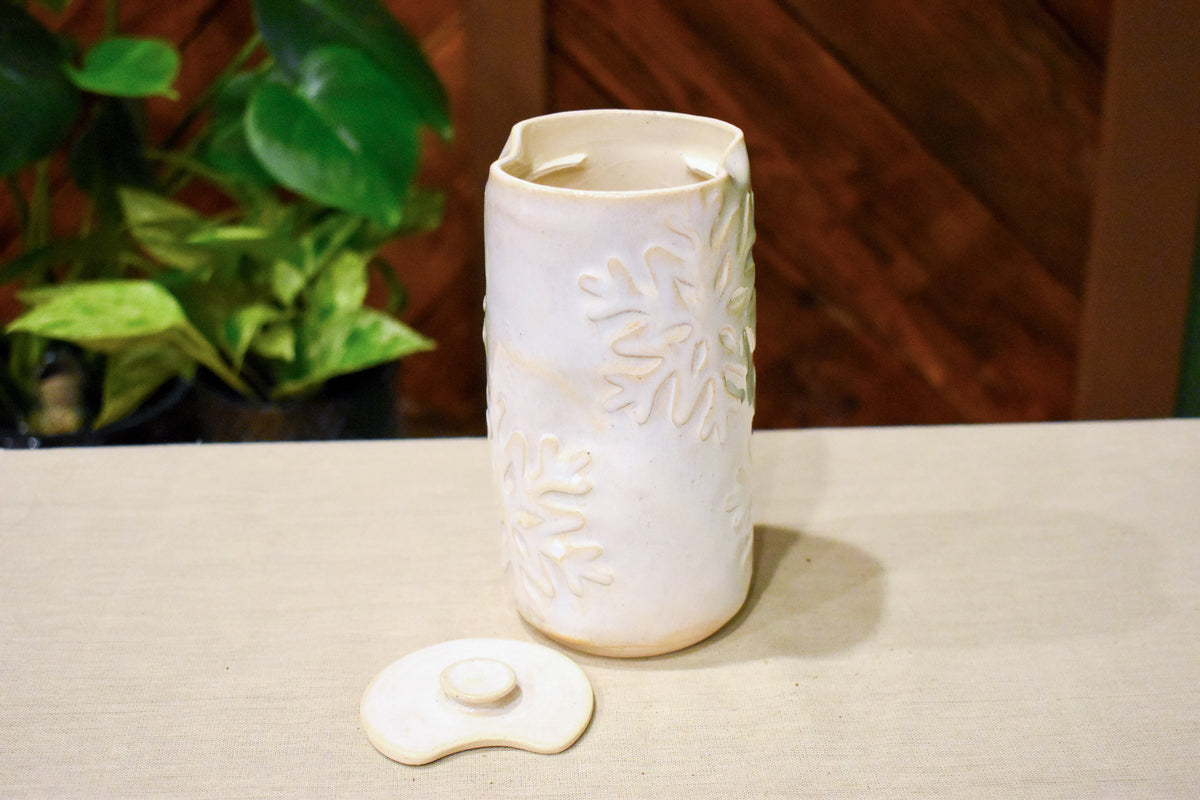 Hand-thrown vase in soft cream-white glaze with raised hand-carved snowflakes and a ceramic lid