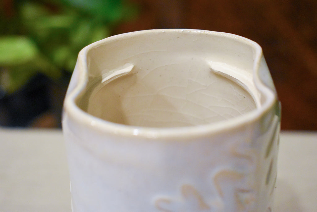 Hand-thrown vase in soft cream-white glaze with raised hand-carved snowflakes and a ceramic lid