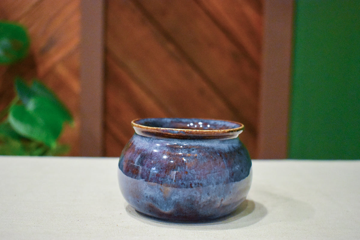 Small hand-thrown belly pot with a curved silhouette, indigo and violet glaze fading to iron-brown with gold at the rim