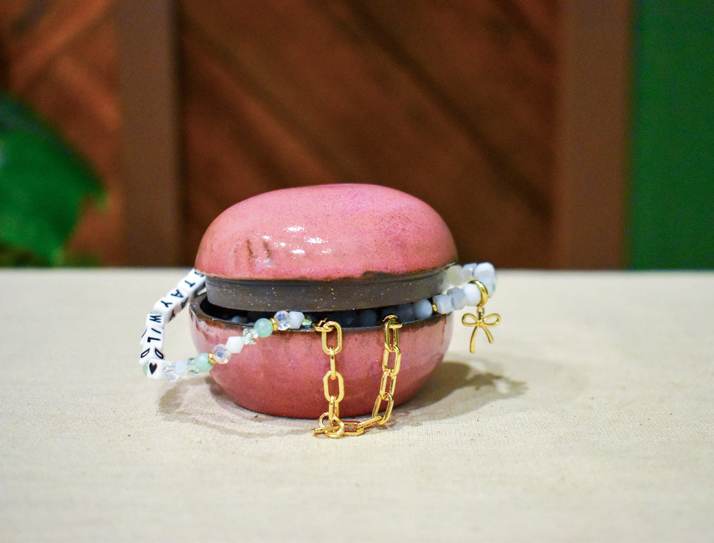 Small hand-thrown lidded jar shaped like a river stone, rosy mauve glaze with a near-black rim