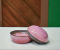 Small hand-thrown lidded jar shaped like a river stone, rosy mauve glaze with a near-black rim