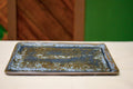 Hand-formed long rectangular catch-all dish in Tide & Earth, deep teal-blue glaze with warm iron speckling