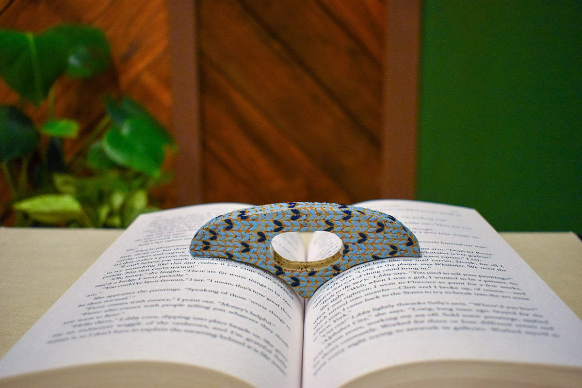 Hand-formed ceramic thumb book holder in Sky Knit, sky-blue knit-stitch texture with navy stitches
