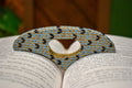 Hand-formed ceramic thumb book holder in Sky Knit, sky-blue knit-stitch texture with navy stitches