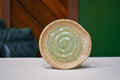 Hand-thrown spiral spoon rest in Sage Pool, soft sage green pooling in the spiral and fading to speckled cream at the rim