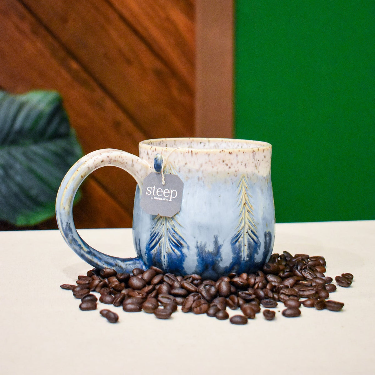 Hand-thrown mug carved with pine trees in fine gold lines in Snowline, deep navy at the base fading to speckled cream at the rim