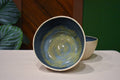 Hand-thrown bowl in Rock Pool, speckled oatmeal cream outside and deep slate blue inside with a swirl of olive and gold