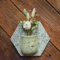 Medium hand-formed wall vase in Pebble, a speckled cream pocket on a pale hexagon back plate