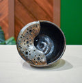 Hand-thrown ceramic berry bowl with a hand-punched drain panel, in glittering near-black Cosmic Tea Dust