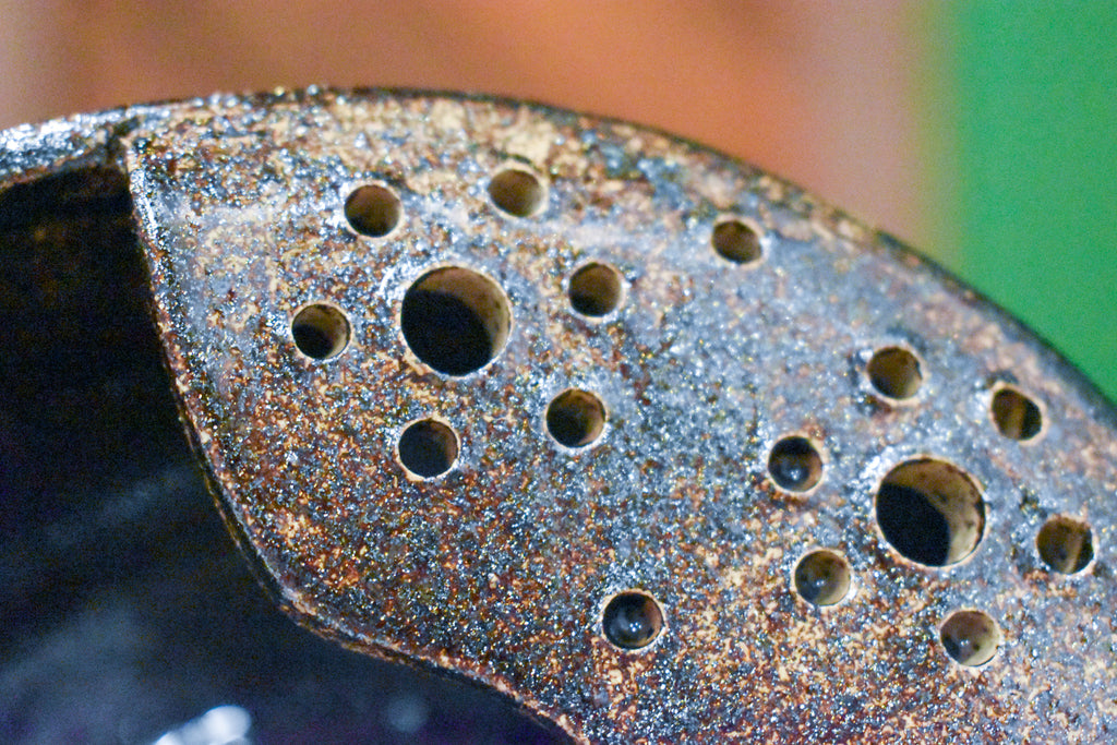 Close-up of the punched drain panel on a Cosmic Tea Dust berry bowl, glittering with silver and bronze flecks
