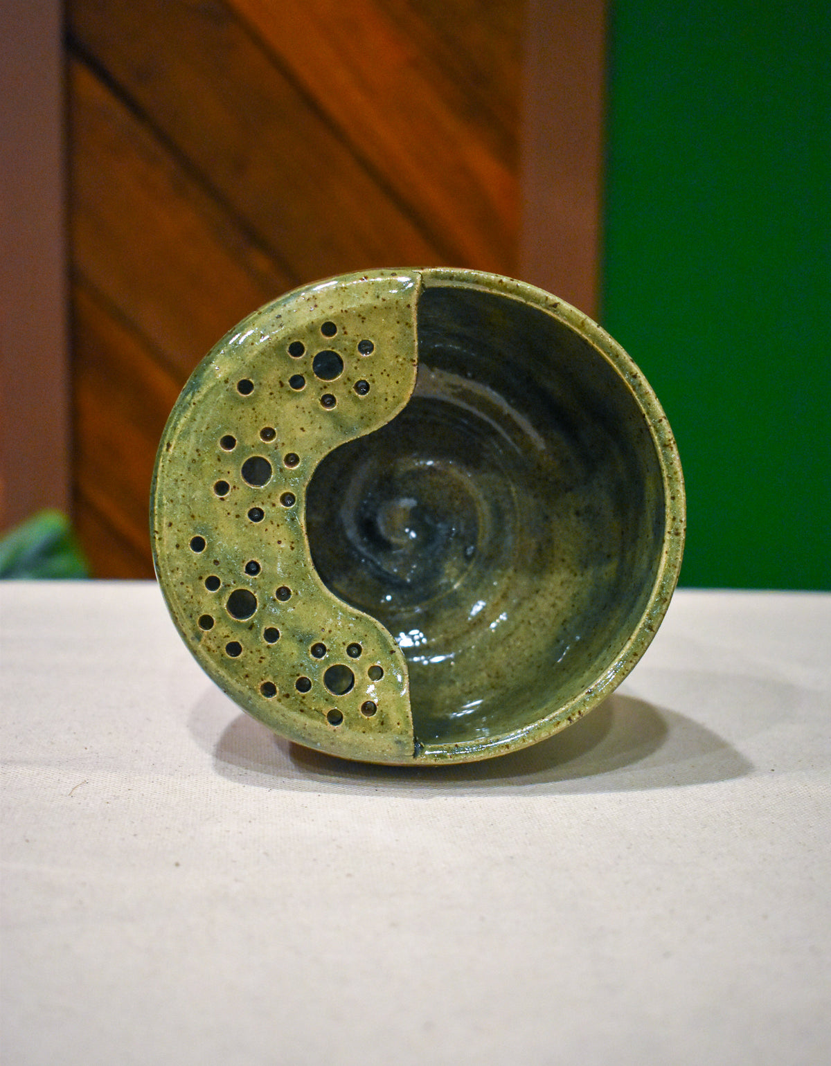 Hand-thrown ceramic berry bowl with a hand-punched drain panel, in moss-green Canopy