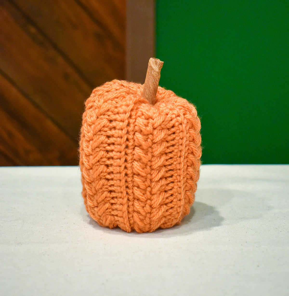 Tall hand-crocheted pumpkin in Desert Glaze, a soft light orange, with a cinnamon-stick stem